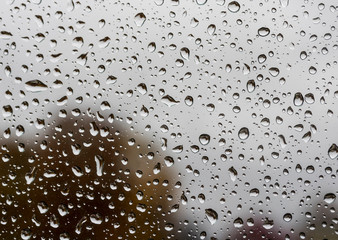 abstract drops on a window glass with blurred background close up , rain macro
