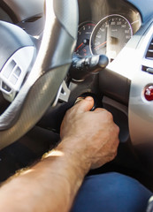 Selective focus male hand winds up the car ignition key, car driving and dashboard. Travel Background