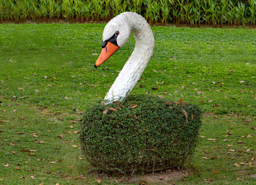 Artificial imitation of swan as romantic decoration of the garden. Model of beautiful white bird in park.