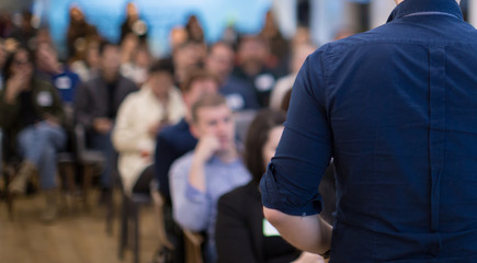 Conference photo audience and speakers giving speech. Seminar presenters on a panel during forum. Corporate managers in sales executive training discussion on stage. Investor pitch presentation.
