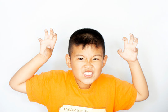 The boy swearing and grimacing for the camera. Funny posting character on white background. Funny kid. Little boy. Ugly grimace child. close up portrait.