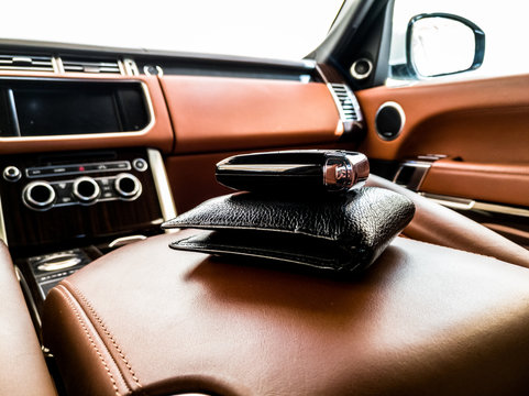 Closeup Of A Black Leather Wallet And A Car Key Kept On The Consul Of An Exotic Vehicle With Brown Interior Of The Car