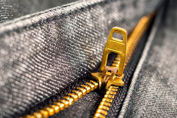Golden zipper close-up on black jeans.
