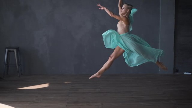 slow motion ballet dancer dancing high jumps in the hall