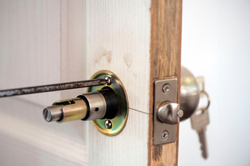 Closeup of a professional locksmith installing or repairing a new deadbolt lock on a house exterior door with the inside internal parts.Man fixing lock with screwdriver.