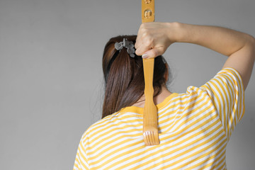 Close up woman uses a scratches to scratch his back in his house .The scratched wood