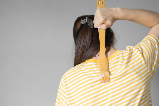 Close up woman uses a scratches to scratch his back in his house .The scratched wood