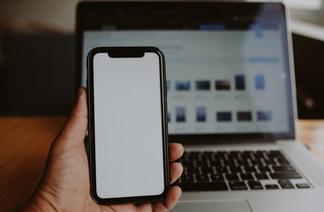 Working on computer and smart phone with white screen background. Closeup of hands using mobile phone and laptop computer with blank copy space screen for your advertising text message or content