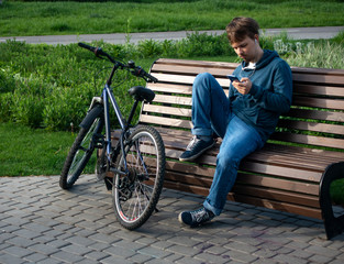 Young Teenager Man With Smartphone And Bike.