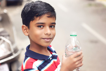 Indian boy drink water from a plastic bottle