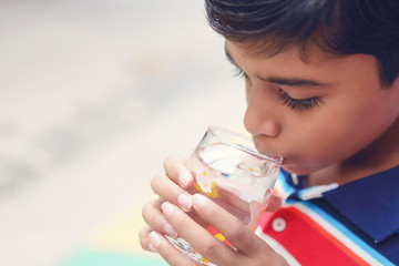 Indian little boy showing drinking glass with water