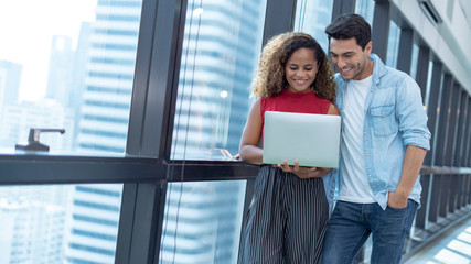 Portrait of young man and young girl in the office.Happy smiling couple using laptop for studying in open work place.