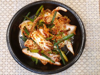 Top view of Korean lettuce pickle with sesame in black plate on the wooden table, Kimchi is korea traditional, Space for text in template, ready to eat or serve