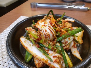 Selective focus of Korean lettuce pickle with sesame in black plate on the wooden table, Kimchi is korea traditional, Space for text in template, ready to eat or serve