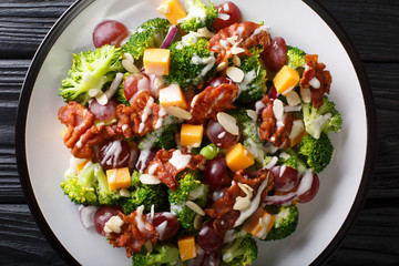 Fresh salad with broccoli, cheddar, grapes, bacon, almonds and onions with cream dressing close-up on the table. Horizontal top view