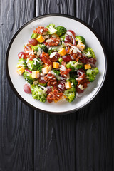 Broccoli, cheddar, grape, bacon, almond and onion salad recipe close-up in a plate. Vertical top view