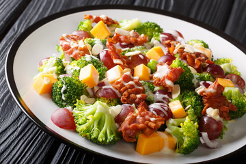 Serving of salad with broccoli, cheddar, grapes, bacon, almonds and onions close-up in a plate. horizontal