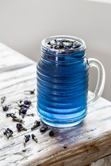 Glass jar of cold  Butterfly pea tea (pea flowers, blue pea) on old rustic table.