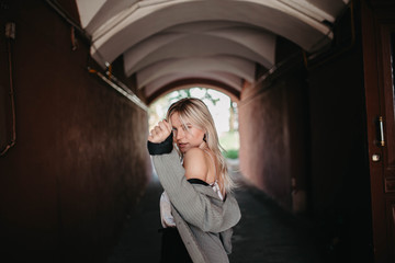 Stylish blonde woman in a gray jacket in the arch at home, street photography.