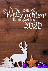German Calligraphy Frohe Weihnachten Und Ein Glueckliches 2020 Means Merry Christmas And Happy 2020. Christmas Decoration With Tree, Deer And Purple Ball. Brown Wooden Background
