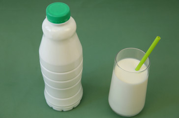 plastic bottle of bio kefir or yogurt and glass of kefir on the green background with copy space for text. Dairy products.