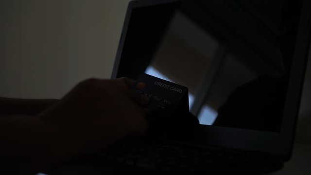hacker with credit card, theft holding credit cards on laptops using data password in unauthorized shopping for payments, hacking in cyber crime security concept