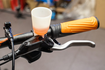 Close up photo of hydraulic brake lever with bleedeing funnel filled with mineral oil. Process of bicycle brake bleeding.