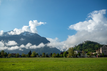 Beautiful view of green field at interlaken town on mountains and clouds blue sky background with...