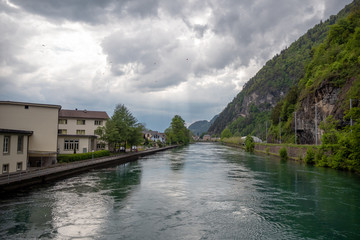Fototapeta na wymiar Charming view of aare river through the interlaken on cloudy sky with sunlight and fresh green mountain background with copy space