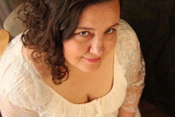 Portrait of a full happy woman in a white dress. plus size model