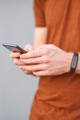 Young man using smartphone near a sloppy painted grey urban wall.
