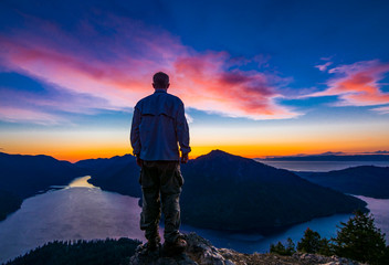 Fototapeta premium Adventurous man watching a sunset from a mountaintop.