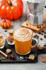 Pumpkin spice latte in a glass mug with cinnamon and nutmeg .