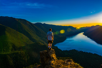 Adventurous man watching a sunset from a mountaintop.