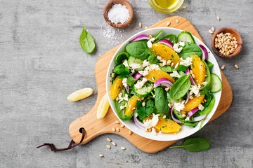 Fotobehang Fresh spinach salad with oranges, feta (ricotta) cheese, red onion and pine nuts . © Nelea Reazanteva