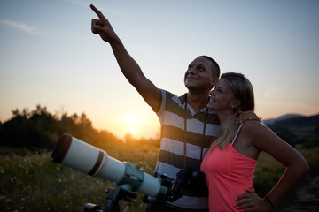 Couple looking at the sky with a telescope in nature.