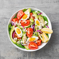 Fresh avocado salad with tomato,cucumber , boiled eggs and spinach served with lemon and ricotta cheese. Top view.