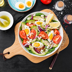 Fresh avocado salad with tomato,cucumber , boiled eggs and spinach served with lemon and ricotta cheese. Top view.