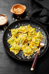 Italian ravioli pasta with spinach and ricotta on black wooden  background. 