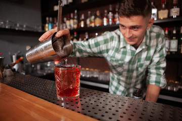 Selective focus on a drink professional bartender pouring to the glass. Cocktails, occupation concept
