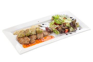 Grilled meat with zucchini and fresh salad on white plate isolated on white background