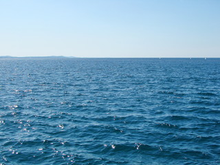 View from the waterfront of the town on the natural combination of various shades of sea blue against the background of clear summer blue sky.
