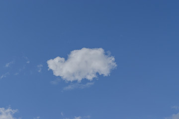 Single white cloud on blue sky background.