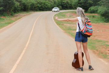 Sexy women looking to travel, hitchhiking roadside.