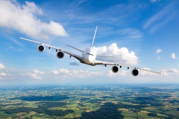White passenger plane in flight. The plane flies against a background of a endless horizon. Aircraft right inclination / front view.