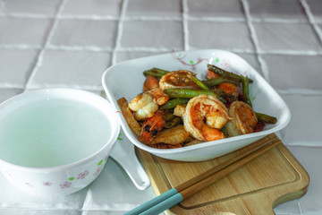 Stir-fried spicy dried chilli french green beans with prawns, and a bowl of porridge.