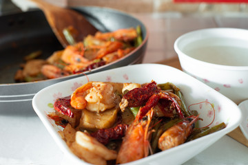 Stir-fried spicy dried chilli french green beans with prawns, and a bowl of porridge.