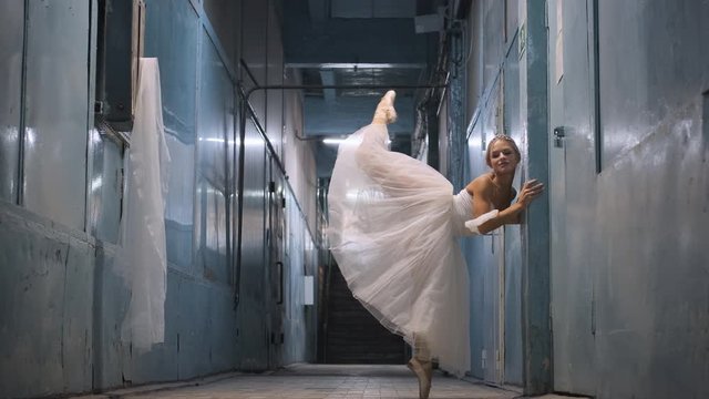 ballerina in a white tutu posing in the hallway of the production hall
