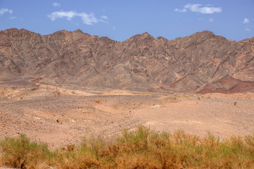 Side view of colorful mountains of Eilat against of blue sky with clouds. Israel