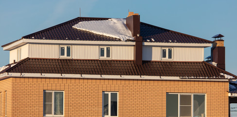 Fototapeta na wymiar Brick house with snow on the roof